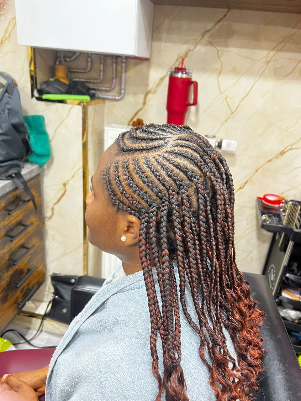 Frau mit kreativen Cornrows und langen, rötlich gefärbten Braids im Afro American Barbershop Nürnberg